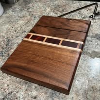 Walnut cutting board with decorative multi-wood inlay strip — handcrafted by Two Mittens in Charlotte, NC